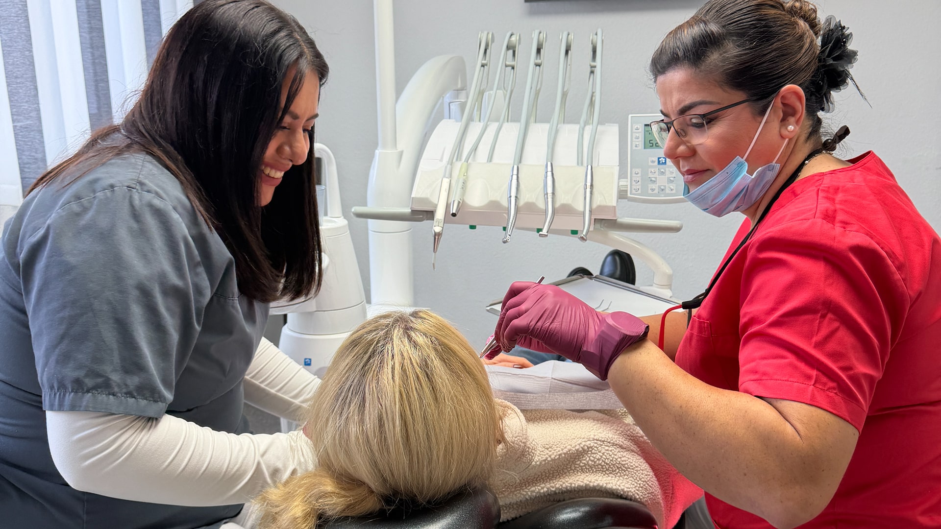 Zahnarztpraxis Farida Rauschning in Seelze – Frau Rauschning erklärt einer Patientin während der Behandlung gemeinsam mit ihrer Assistenz ruhig den Ablauf des ersten Besuchs in freundlicher Atmosphäre